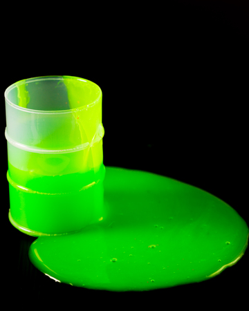 Green slime spllling out of barrel on black backgroundの写真素材