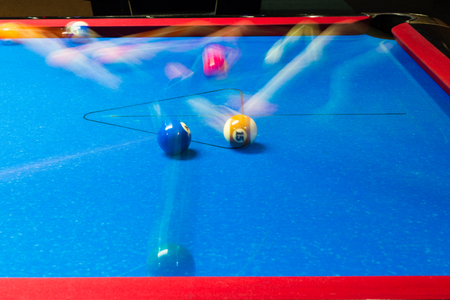 Motion blurred balls on a pool table with blue felt