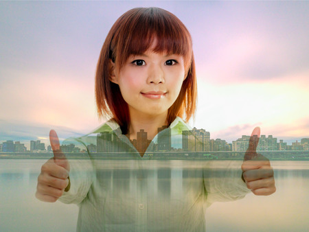 Chinese woman giving thumbs up sign on cityscape double exposureの写真素材