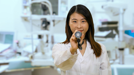 Chinese female doctor in hospital clinic  holding out stethoscope