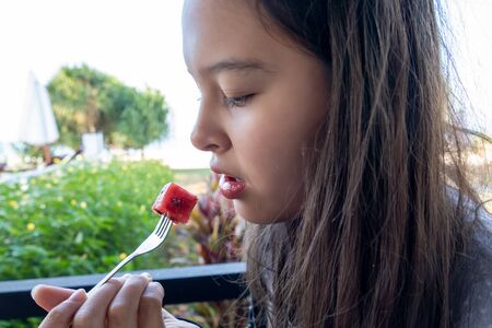 Asian American Tween girl eats watermelon with a forkの写真素材