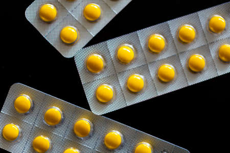 Yellow tablets in blister pack on black backgroundの写真素材