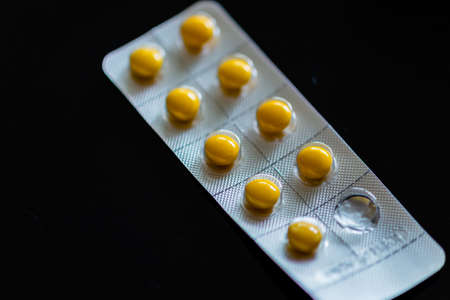 Yellow tablets in blister pack on black backgroundの写真素材