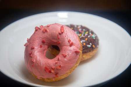 Strawberry and chocolate donuts on white plateの写真素材
