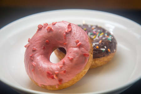 Strawberry and chocolate donuts on white plateの写真素材