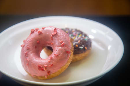 Strawberry and chocolate donuts on white plate