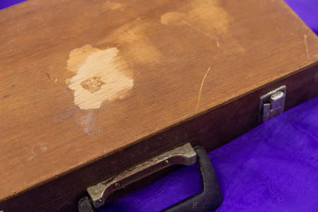 Old wooden box with handle on purple fabric background