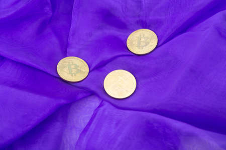 Three Bitcoins on a purple fabric backgroundの写真素材
