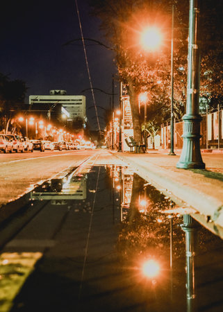 After a rain, a road puddle reflections the lights and buildingsの写真素材
