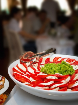 Caprese salad close up shot on a wedding banquet table with blurred people in backgroundの写真素材