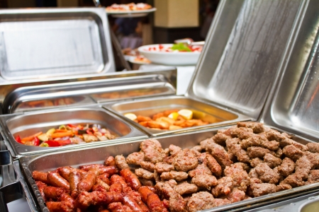 Food warmers on catering event offer kebab, sausage and grilled vegetablesの写真素材