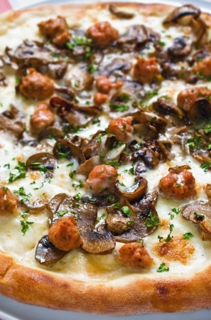 Sausage and mushrooms pizza on a restaurant table plateの写真素材
