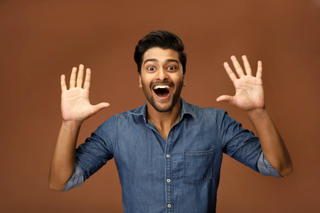 A young guy in a denim shirt is showing ten fingers while looking at the camera.の写真素材