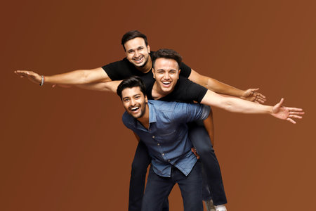 Three men are posing while smiling and spreading their arms.の写真素材