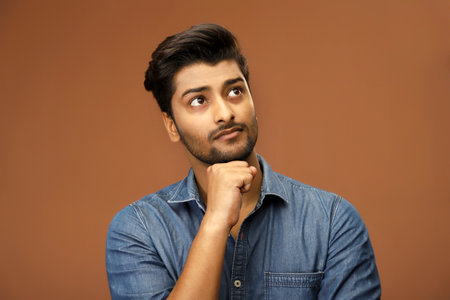 A man is thinking something with his hand under his chin.の写真素材