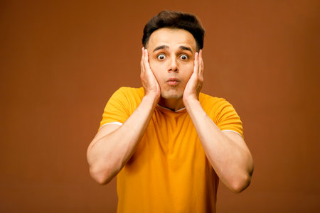 A person is keeping both hands on his cheeks with a surprised facial expression.
