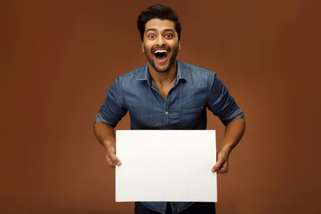 An amazing male model is holding blank white board in his hand for advertisement.の写真素材