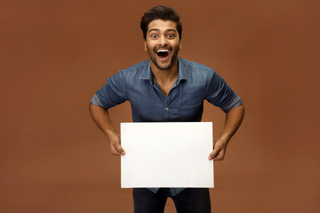 Smiling male model with surprised facial expression with open-mouth holding a blank sheet of paper .の写真素材