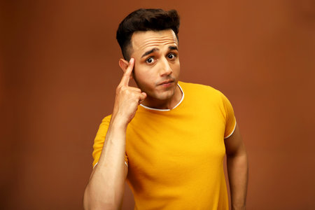 An indian guy is thinking while keeping finger on his head.の写真素材