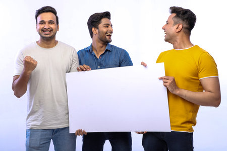 Joyful friends are smiling and holding up a blank sign while posing.の写真素材