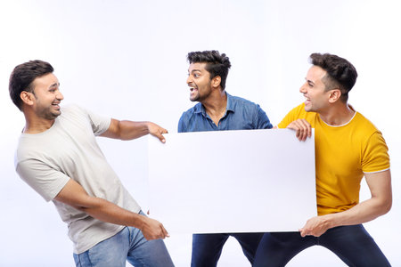 Three besties are standing and holding a white paper board for an advertisement.の写真素材