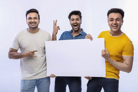 Stylish male models are smiling and holding up a blank sign while posing.の写真素材