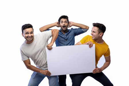 Three smiling men are posing while holding a blank white banner over a white wall.の写真素材