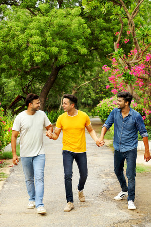 Three cheerful friends holding each other's hands while walking in nature.の写真素材
