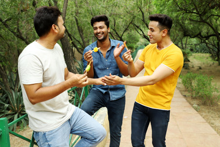 A group of three men are enjoying eating ice cream and having fun in the park.の写真素材