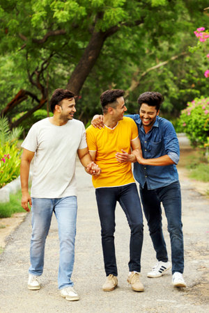 Three cheerful friends are laughing together while walking and enjoying the park.の写真素材