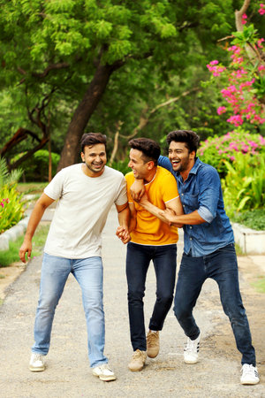 Three men in the park are enjoying themselves and laughing while talking.の写真素材