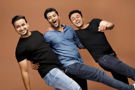 Three men are enjoying wearing casual outfits and posing while standing in front of the camera.の写真素材