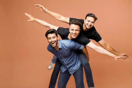 Three handsome men are having fun while standing, posing, and smiling.の写真素材