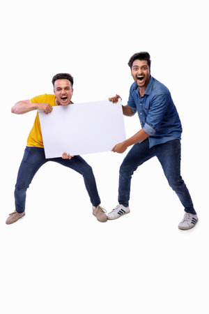 Two buddies in casual clothing are shouting while holding a blank board their hands.の写真素材