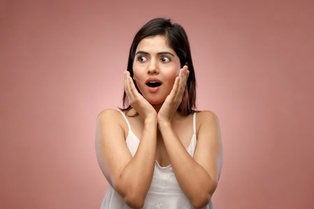 Surprised young woman with open mouth looking at camera isolated on pink backgroundの写真素材