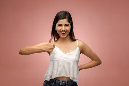Young beautiful asian woman showing thumb up gesture isolated on pink backgroundの写真素材