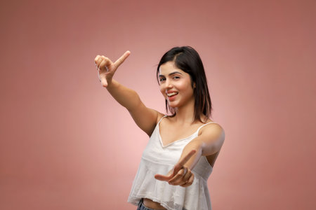Young beautiful asian woman with white shirt pointing up on pink backgroundの写真素材