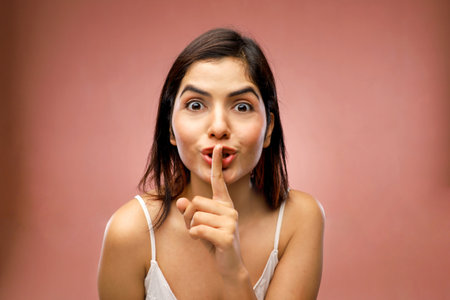 Portrait of a young woman asking for silence with finger on lipsの写真素材