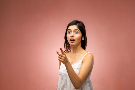 Surprised young girl in a white dress. Studio shot on a pink background.の写真素材