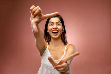 Portrait of a beautiful young woman showing victory sign with both handsの写真素材