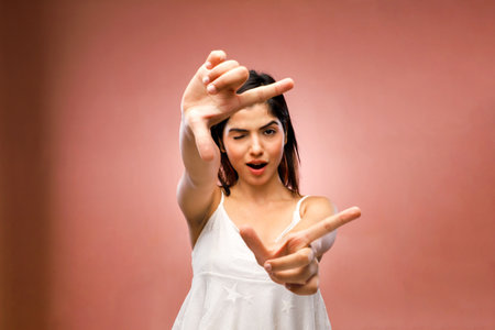 Portrait of a beautiful young woman making a frame with her fingersの写真素材