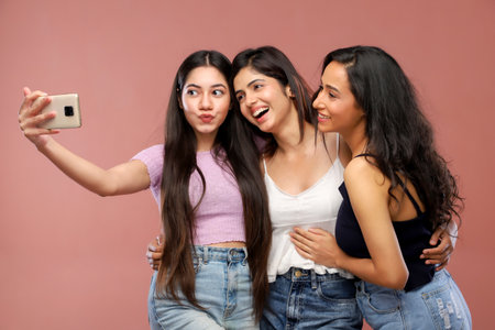 Group of happy women taking selfie with mobile phone isolated over pink backgroundの写真素材