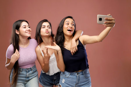 Group of young women taking a selfie with a smart phone over brown backgroundの写真素材