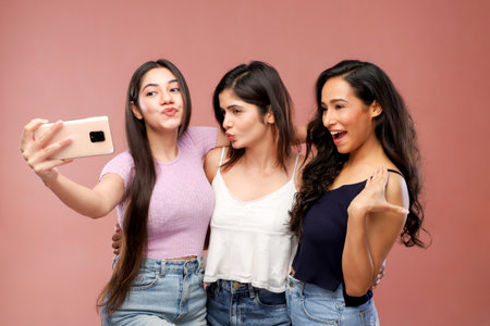 Group of young asian women taking selfie with mobile phone on pink backgroundの写真素材