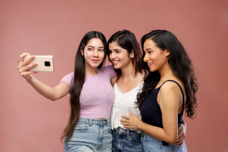 Portrait of three young beautiful asian women taking selfie with mobile phoneの写真素材
