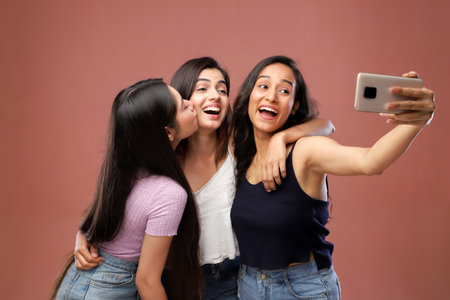Portrait of three young asian women taking selfie with mobile phoneの写真素材