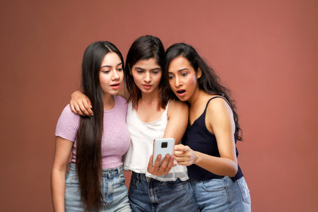 Portrait of three young asian women using smartphone on brown backgroundの写真素材