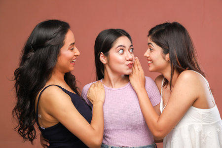 Three young asian women gossiping and gossiping on brown backgroundの写真素材