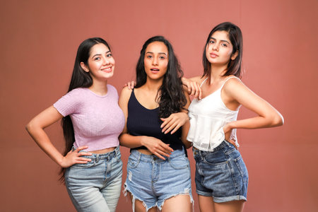 Group of young beautiful asian women in jeans and tank top on brown backgroundの写真素材