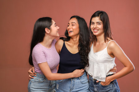 Portrait of three beautiful young women smiling and looking at each otherの写真素材